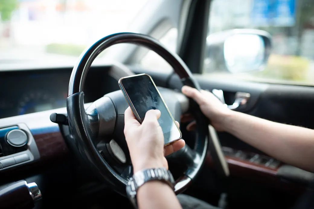 運転中にスマートフォンを操作するドライバーの手元
